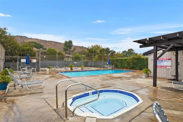 view of pool featuring a mountain view, a hot tub, and a patio area