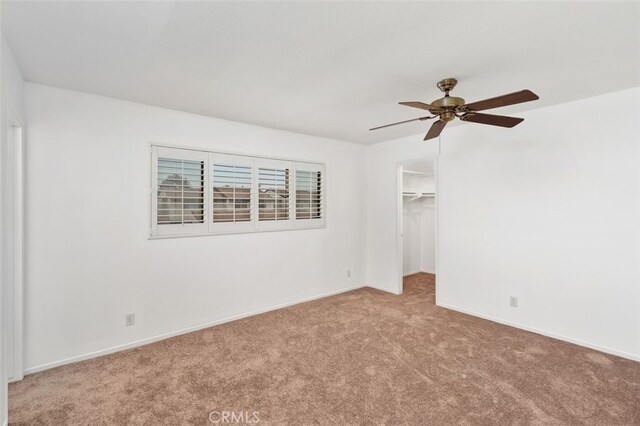 unfurnished bedroom with ceiling fan, a closet, light carpet, and a spacious closet