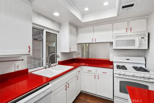 kitchen featuring sink, dark wood-type flooring, a raised ceiling, white appliances, and white cabinets