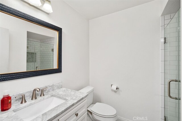 bathroom with vanity, toilet, and a shower with door