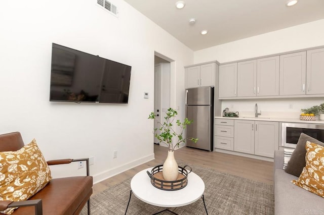 living room with indoor wet bar, beverage cooler, and light hardwood / wood-style flooring