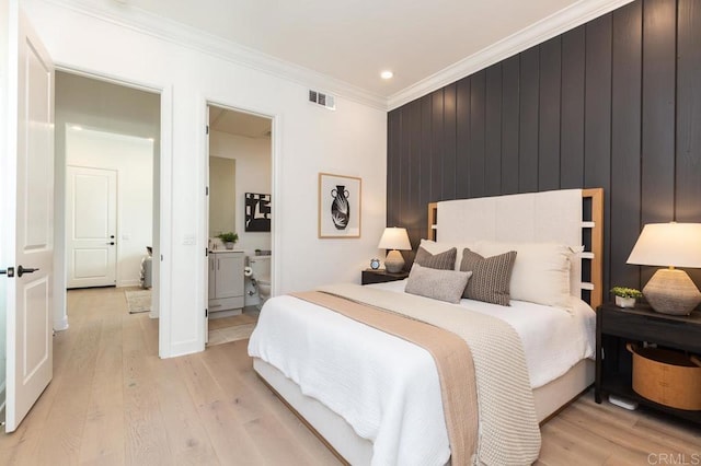 bedroom featuring crown molding, connected bathroom, light hardwood / wood-style floors, and wood walls