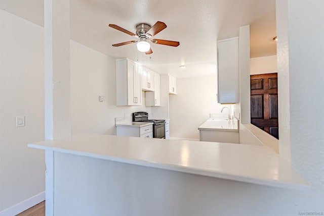 kitchen with kitchen peninsula, white cabinetry, ceiling fan, and electric range oven