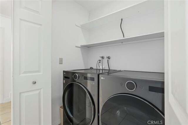 laundry room with washing machine and dryer and light tile patterned floors