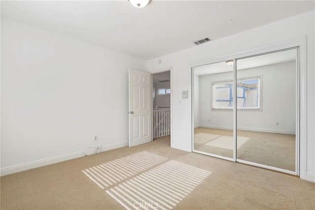 unfurnished bedroom with light carpet and a closet