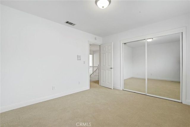 unfurnished bedroom featuring light colored carpet and a closet