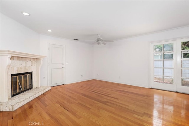 unfurnished living room with hardwood / wood-style floors, ceiling fan, a premium fireplace, and ornamental molding