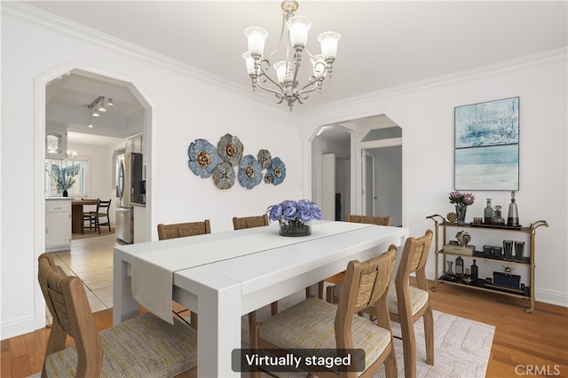 dining area with light hardwood / wood-style floors, a notable chandelier, and ornamental molding