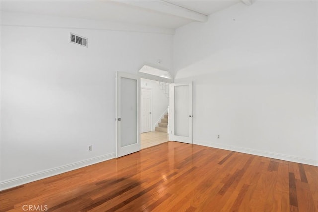 unfurnished room with beam ceiling, hardwood / wood-style floors, and high vaulted ceiling