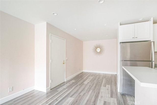 kitchen featuring white cabinetry, stainless steel refrigerator, and light hardwood / wood-style flooring