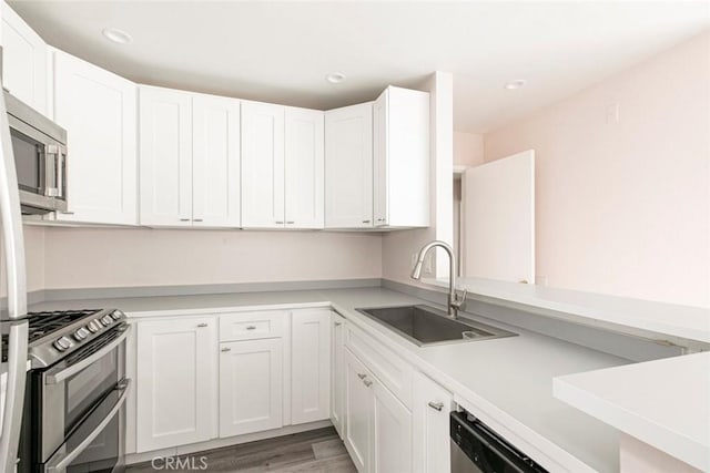 kitchen with white cabinetry, sink, stainless steel appliances, and light hardwood / wood-style floors