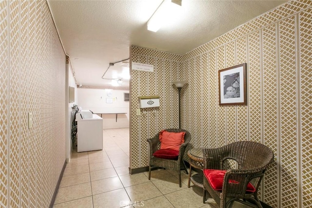 corridor with light tile patterned flooring, a textured ceiling, and washer / clothes dryer