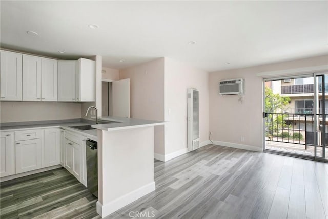 kitchen with a wall unit AC, kitchen peninsula, dishwasher, and white cabinets