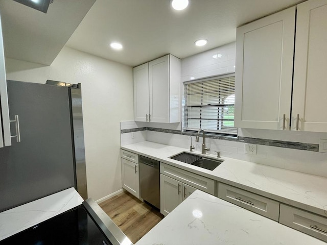 kitchen featuring hardwood / wood-style floors, white cabinets, sink, light stone counters, and stainless steel appliances