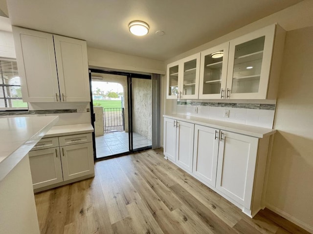 kitchen with white cabinets, decorative backsplash, and light hardwood / wood-style floors