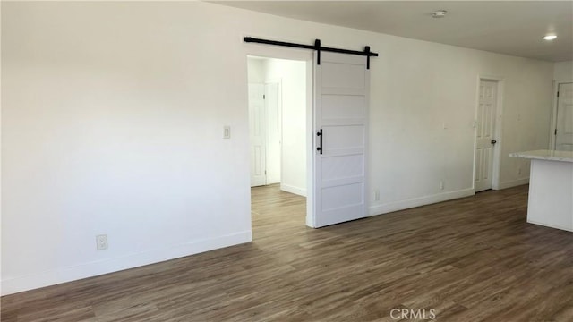 unfurnished room featuring dark wood-type flooring and a barn door