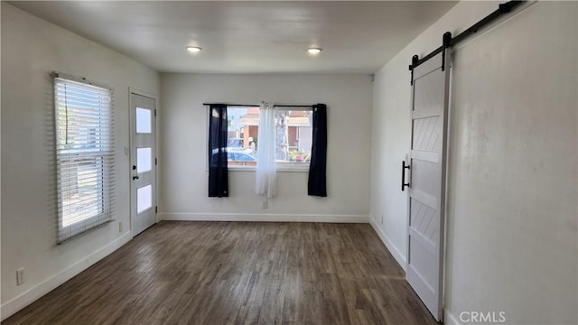 empty room featuring dark wood-type flooring and a barn door