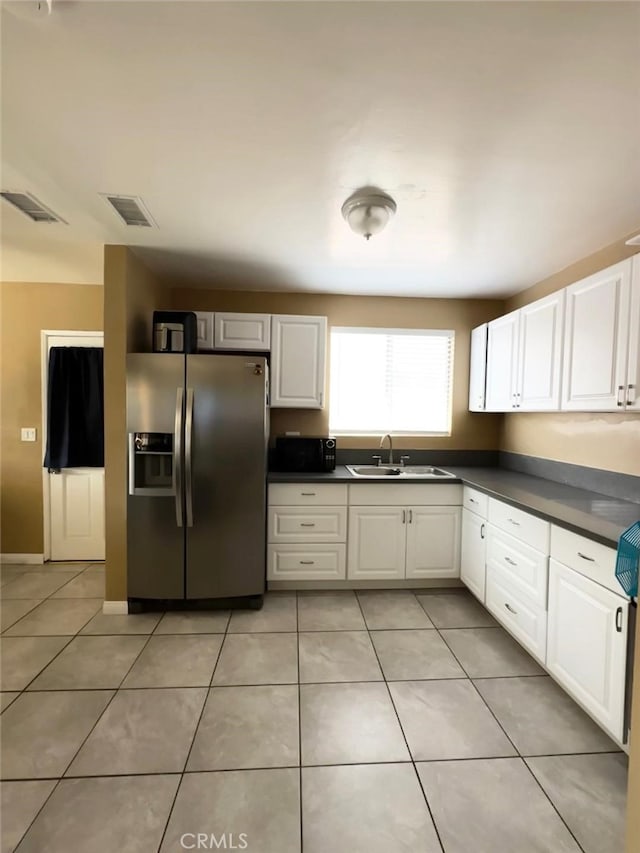 kitchen featuring stainless steel fridge with ice dispenser, light tile patterned floors, white cabinetry, and sink