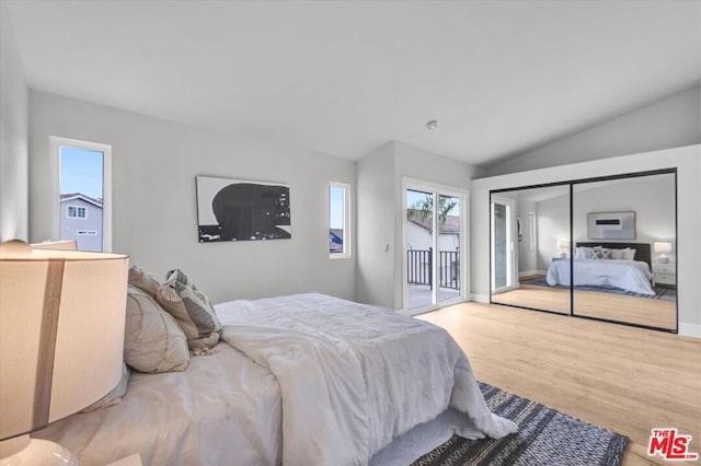 bedroom with access to exterior, a closet, vaulted ceiling, and hardwood / wood-style flooring