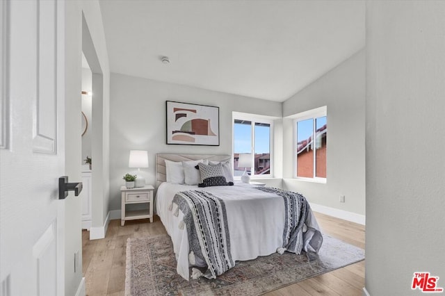 bedroom with light hardwood / wood-style floors and vaulted ceiling