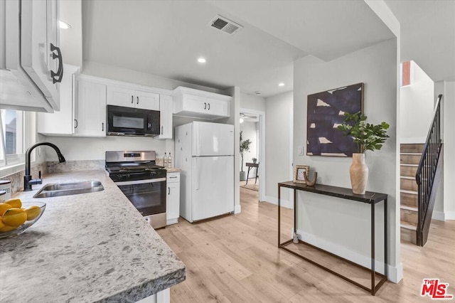 kitchen featuring sink, stainless steel gas range oven, light hardwood / wood-style flooring, white fridge, and white cabinets