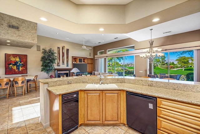 kitchen featuring sink, black dishwasher, light stone counters, pendant lighting, and ceiling fan with notable chandelier