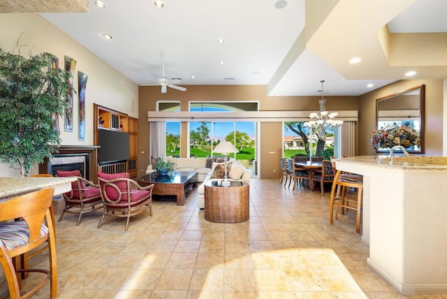 tiled living room featuring a fireplace and ceiling fan with notable chandelier