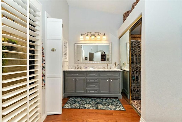 bathroom with hardwood / wood-style floors, vanity, and lofted ceiling