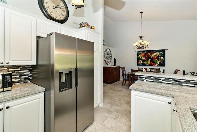 kitchen with pendant lighting, white cabinets, vaulted ceiling, a notable chandelier, and stainless steel appliances