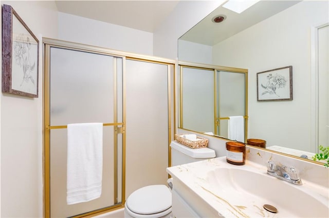 bathroom featuring a shower with door, vanity, and toilet