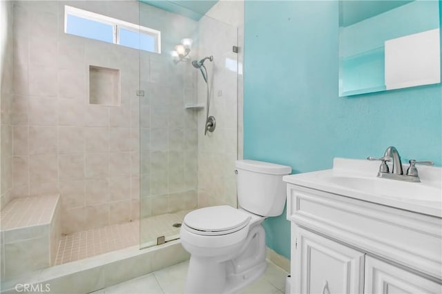 bathroom featuring tile patterned flooring, a tile shower, vanity, and toilet