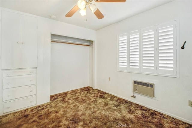 unfurnished bedroom with ceiling fan, dark carpet, an AC wall unit, and a closet