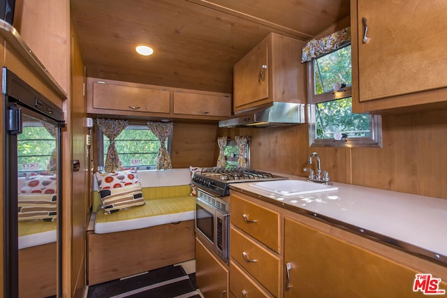 kitchen with sink, gas stove, wood walls, and wood ceiling