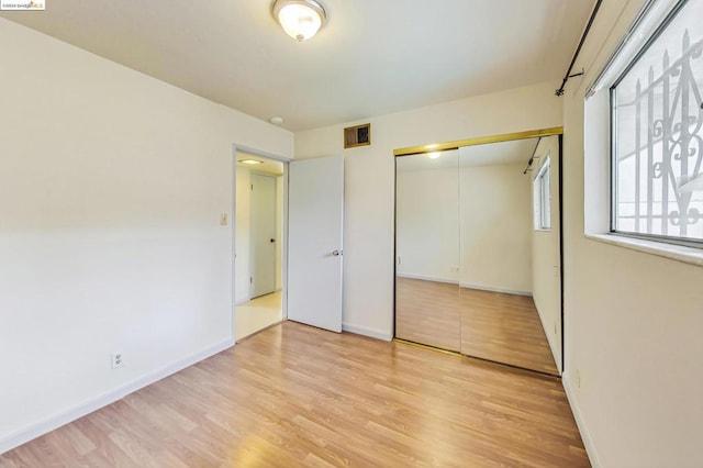 unfurnished bedroom featuring light wood-type flooring and a closet