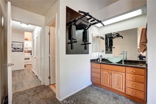 bathroom with hardwood / wood-style floors, vanity, and a textured ceiling