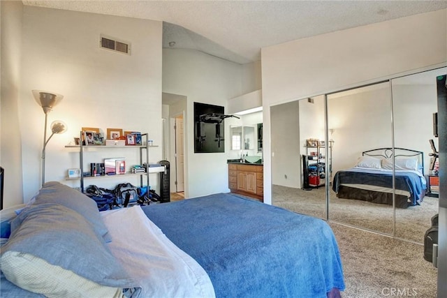 bedroom with carpet, ensuite bathroom, high vaulted ceiling, and a closet