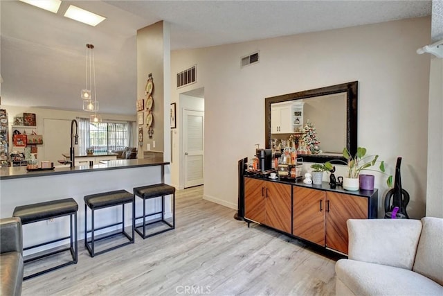 11350 Foothill Blvd Unit 30, Sylmar, CA 91342 - kitchen with lofted ceiling, dark countertops, light wood-type flooring, decorative light fixtures, and brown cabinetry