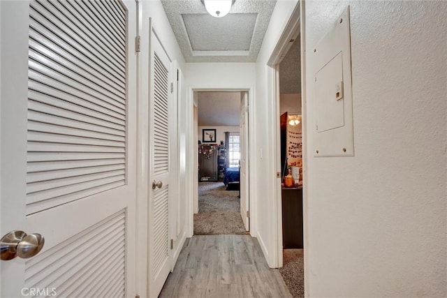 hall featuring a textured ceiling and light hardwood / wood-style floors