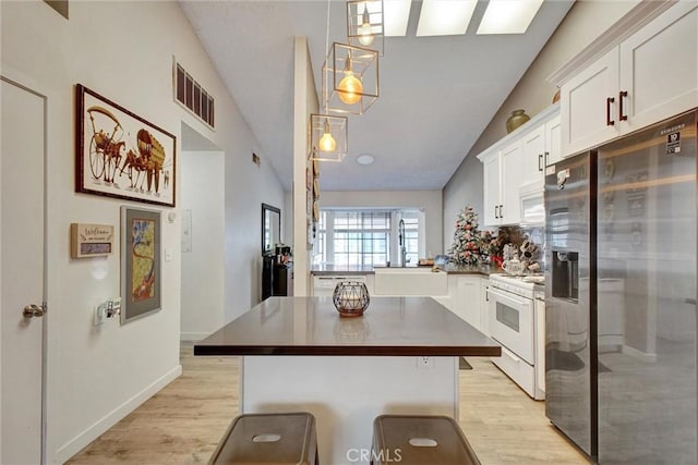 kitchen featuring white appliances, light hardwood / wood-style floors, and vaulted ceiling