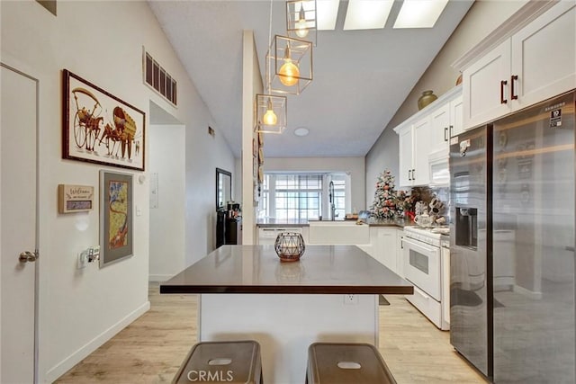 11350 Foothill Blvd Unit 30, Sylmar, CA 91342 - kitchen with white appliances, light wood-type flooring, white cabinetry, vaulted ceiling, and a center island