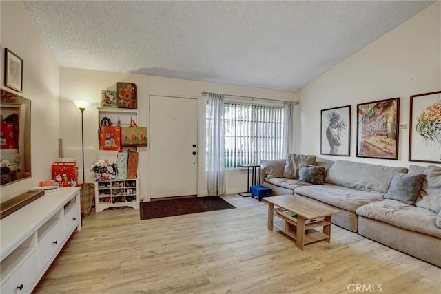 living room with a textured ceiling, lofted ceiling, and light wood-type flooring