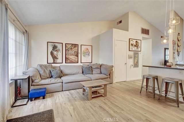 living room with light wood-type flooring and high vaulted ceiling