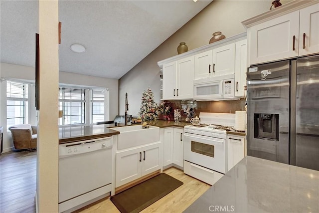 kitchen featuring white cabinets, light wood-type flooring, white appliances, and vaulted ceiling