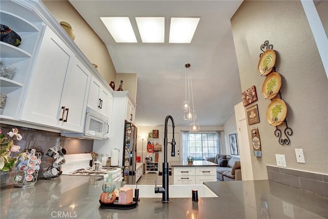 11350 Foothill Blvd Unit 30, Sylmar, CA 91342 - kitchen with white microwave, a peninsula, backsplash, dark countertops, and open shelves