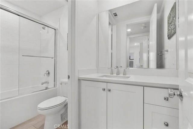 full bathroom featuring vanity, toilet, and combined bath / shower with glass door