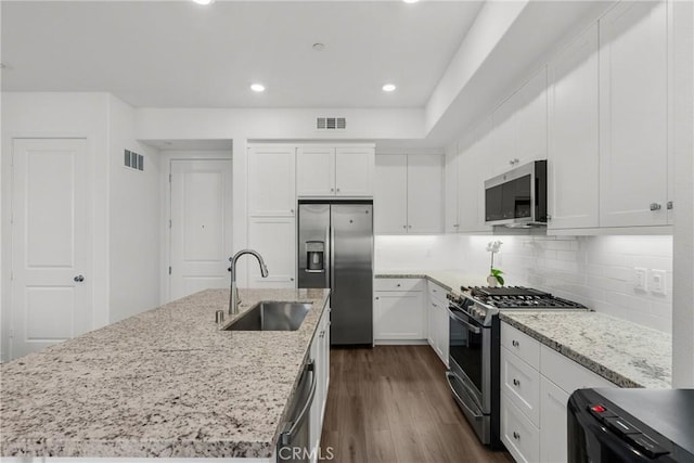 kitchen featuring stainless steel appliances, a kitchen island with sink, dark wood-type flooring, sink, and white cabinetry