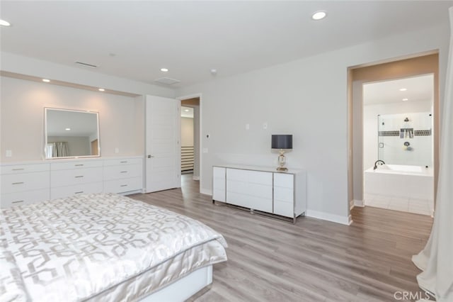 bedroom featuring ensuite bathroom and light hardwood / wood-style flooring