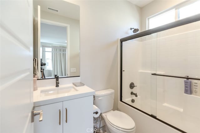 full bathroom with combined bath / shower with glass door, vanity, and toilet