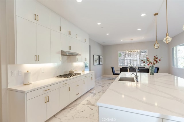 kitchen featuring sink, a large island with sink, decorative light fixtures, stainless steel gas stovetop, and white cabinets