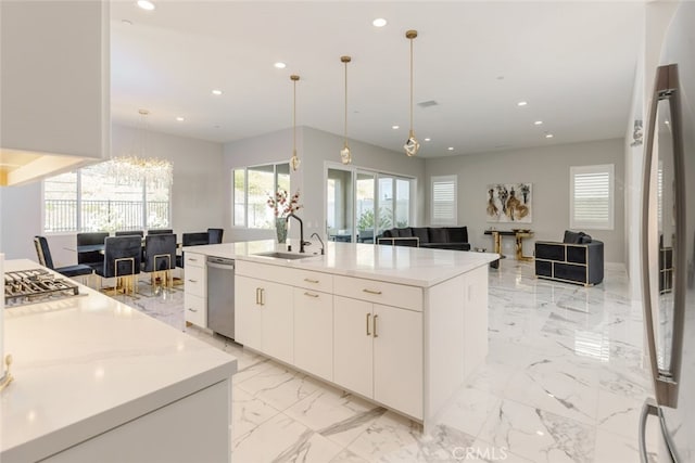 kitchen with stainless steel dishwasher, sink, decorative light fixtures, white cabinets, and an island with sink